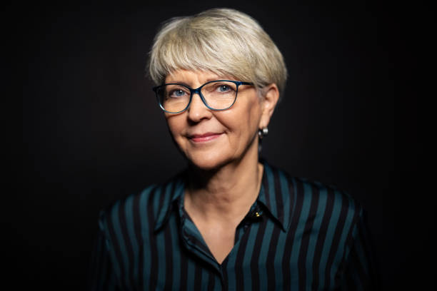 Portrait of senior woman wearing eyeglasses on dark background. Mature caucasian woman with short hair staring at camera.